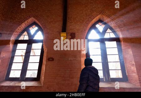 16. Dezember 2021, Srinagar, Jammu und Kashmir, Indien: Ein Mann, der auf das Sonnenlicht blickt, das durch das Fenster der 125 Jahre alten St. Lukes Church, die seit mehr als 30 Jahren in Srinagar geschlossen ist, aufsteigt. Der Grundstein wurde von Dr. Earnest und Dr. Arthur Neve „zur Ehre Gottes“ errichtet und „als Zeuge für Kaschmir“ am 12. September 1896 vom Bischof von Lahore eingeweiht. Nach der Aufhebung des Sonderstatus Kaschmirs fürchten die Christen in der Region, dass der Wandel zu einer Welle hinduistischen Nationalismus und damit zu einer Zunahme der Verfolgung führen wird. (Bild: Stockfoto