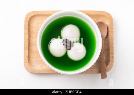 Draufsicht auf Matcha Big tangyuan (tang Yuan) mit süßer Matcha-Suppe und roter Bohnenpaste in einer Schüssel auf weißem Tischhintergrund für Festessen. Stockfoto