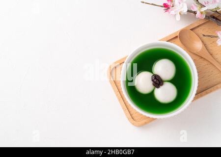 Draufsicht auf Matcha Big tangyuan (tang Yuan) mit süßer Matcha-Suppe und roter Bohnenpaste in einer Schüssel auf weißem Tischhintergrund für Festessen. Stockfoto