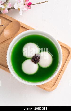 Draufsicht auf Matcha Big tangyuan (tang Yuan) mit süßer Matcha-Suppe und roter Bohnenpaste in einer Schüssel auf weißem Tischhintergrund für Festessen. Stockfoto