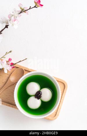 Draufsicht auf Matcha Big tangyuan (tang Yuan) mit süßer Matcha-Suppe und roter Bohnenpaste in einer Schüssel auf weißem Tischhintergrund für Festessen. Stockfoto