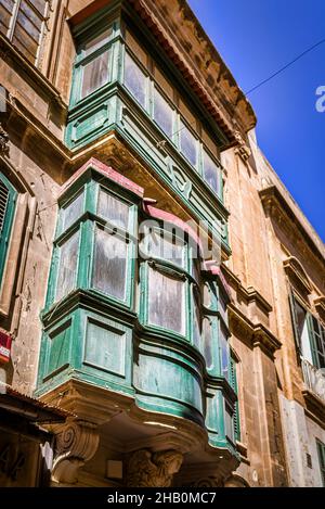 Typisch maltesische Wohnarchitektur mit bunten Holzfrontüren, Lamellenfenstern und geschlossenen Holzbalkonen - Valletta, Malta. Stockfoto
