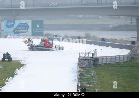 Dresden, Deutschland. 16th Dez 2021. Ein Pistenbully bereitet eine zukünftige Wettkampfstrecke mit Kunstschnee am Ufer der Elbe vor. Am 18. Und 19. Dezember 2021 findet in Dresden der FIS Skilanglauf-Sprint-Weltcup statt. Quelle: Sebastian Kahnert/dpa-Zentralbild/dpa/Alamy Live News Stockfoto