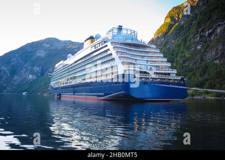 An einem schönen Sommertag steht das Schiff vor Anker. Spiegelungen der Berge im Fjord. Üppig grüne Landschaft mit Gipfeln, die über dem Wasser emporragen. Stockfoto