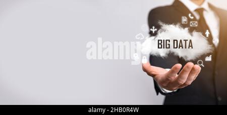 Geschäftsmann hält die Inschrift , Wort BIG DATA . Vorhängeschloss, Gehirn, Mann, Planet, Graph, Lupe, Zahnräder, Symbol für Cloud, Grid, Dokument, Brief, Telefon Stockfoto
