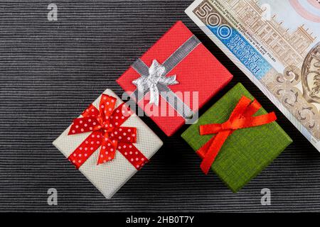 Polnischer 500PLN-Banknote mit Geschenken auf grauem Hintergrund. Kleine Kisten mit Schleifen. Foto aufgenommen unter künstlichem, weichem Licht Stockfoto