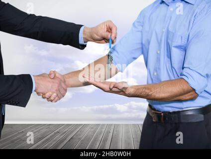 Mittelteil des Immobilienmaklers, der einem Mann Schlüssel gegen Wolken am Himmel gibt Stockfoto