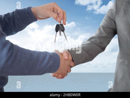 Mitte des Händlers, der einem Mann die Autoschlüssel gegen Wolken am Himmel gibt Stockfoto