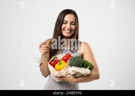 Frau mit Netzbeutel voller Gemüse, Gemüse und Obst ohne Plastiktüten in den Händen. Kein Abfall, frei von Kunststoff. Umweltfreundliches Konzept Stockfoto