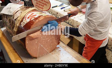 Riesige italienische Mortadella, handwerkliche Scheiben mit riesigem Messer Stockfoto