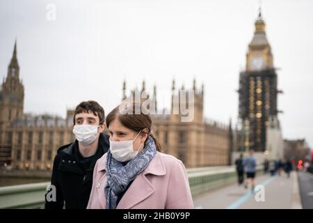 Menschen mit Gesichtsmasken gehen in der Nähe der Houses of Parliament in Westminster, London, nach Inkrafttreten neuer Beschränkungen, um die Ausbreitung der Omicron-Variante des Coronavirus zu verlangsamen. Bilddatum: Donnerstag, 16. Dezember 2021. Stockfoto