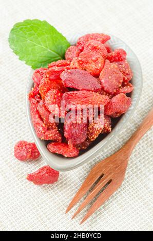 Getrocknete Erdbeeren mit grünem Blatt in Tasse auf Tischdecke. Stockfoto