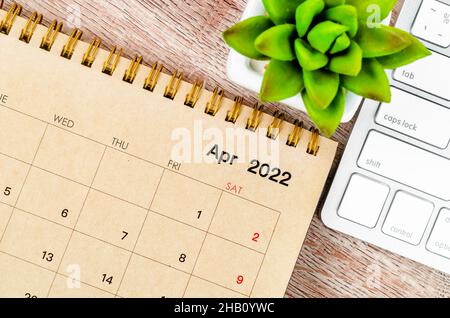 Der Tischkalender April 2022 mit Keyboardcomputer auf Holzhintergrund. Stockfoto