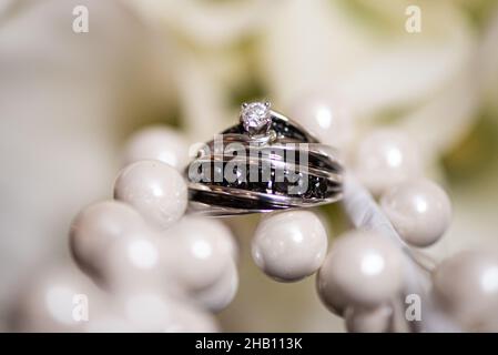 Silberne und schwarze Eheringe auf weißen Perlen Stockfoto