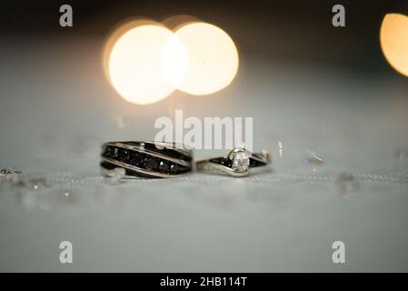 Silberne und schwarze Eheringe auf weißem Tisch Stockfoto