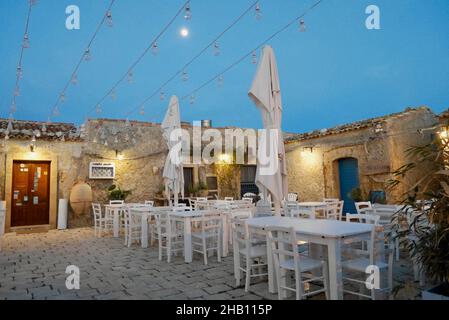 Marzamemi, Italien, 29.03.2018. Schöner Sitzbereich im Freien in einem charmanten Restaurant bei Vollmond. Stockfoto