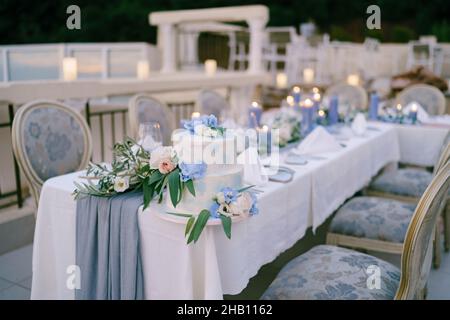 Auf einem Tisch steht weiße, mit Blumen geschmückte Hochzeitstorte Stockfoto