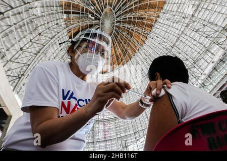 Pasay City, Philippinen. 16th Dez 2021. Ein Mann wird am 16. Dezember 2021 in einem Impfgebiet in einem Einkaufszentrum in Pasay City, Philippinen, mit einem COVID-19-Impfstoff geimpft. Die Philippinen haben die ersten beiden bestätigten Fälle der Omicron-Variante bei zwei Reisenden aus Nigeria bzw. Japan registriert, teilte das Gesundheitsministerium (DOH) am Mittwoch mit. Quelle: Rouelle Umali/Xinhua/Alamy Live News Stockfoto