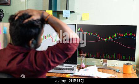Focus on Monitor, Young man enttäuscht für gescheiterte Trading-Strategie beim Betrachten von Graph on Computers im Home Office - Konzept der Geldanlage Stockfoto