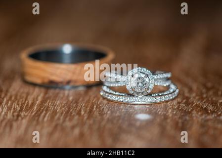 Hochzeitsband aus Holz hinter Bräuten mit Ring aus Weißgold mit Diamant auf Holzoberfläche Stockfoto