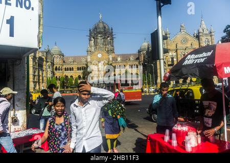 Mumbai, Maharashtra, Indien : die Menschen gehen an einem Stand für kalte Getränke vor dem UNESCO-Weltkulturerbe Chhatrapati Shivaji Terminus Bahnhof (früher Stockfoto
