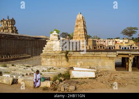 Hampi, Karnataka, Indien: Ein Mann sitzt außerhalb des Sree Virupaksha Tempels aus dem 7th. Jahrhundert. Es wird angenommen, dass es seit seiner Gründung ununterbrochen funktioniert Stockfoto