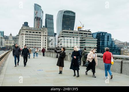 London, Großbritannien. 16. Dezember 2021. Die Menschen überqueren die London Bridge mit den Wolkenkratzern der City of London in der Ferne. Die Bank of England hat angekündigt, dass sie den Zinssatz als Reaktion auf den Anstieg der Inflation auf 5,1 % von 0,1 % auf 0,25 % angehoben hat, und sie haben bereits prognostiziert, dass die Inflationsrate im nächsten Jahr auf 6 % steigen wird. Kredit: Stephen Chung / Alamy Live Nachrichten Stockfoto