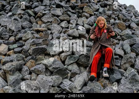 Berlin, Deutschland. Ein junger, erwachsener Punk-Typ sitzt auf einem Felshaufen in der Nähe eines riesigen Graffity-Ortes, irgendwo in Spandau. Stockfoto