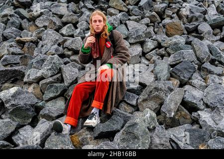 Berlin, Deutschland. Ein junger, erwachsener Punk-Typ sitzt auf einem Felshaufen in der Nähe eines riesigen Graffity-Ortes, irgendwo in Spandau. Stockfoto