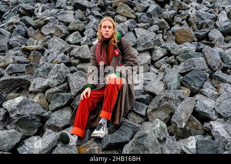 Berlin, Deutschland. Ein junger, erwachsener Punk-Typ sitzt auf einem Felshaufen in der Nähe eines riesigen Graffity-Ortes, irgendwo in Spandau. Stockfoto