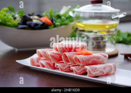 Geschnittene Lammfleischrollen für den Hotpot auf weißem Teller in Nahaufnahme Stockfoto