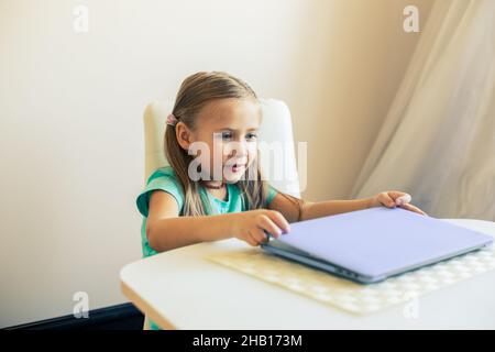 Kleines nettes Mädchen öffnet Laptop, um Videoanruf zu haben Stockfoto