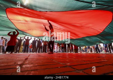 Savar, Bangladesch. 16th Dez 2021. Die Menschen winken Nationalflaggen, während sie sich versammeln, um am nationalen Denkmal der Märtyrer des Unabhängigkeitskrieges 1971 ihren Respekt zu zollen, um den Tag des Sieges 50th zu feiern, der das Ende eines bitteren neunmonatigen Unabhängigkeitskrieges von Pakistan am 16. Dezember 2021 in Savar markiert. Bangladesch feiert den 50th. Jahrestag seines nationalen Sieges und erinnert sich an die tapferen Freiheitskämpfer, die gekämpft und das ultimative Opfer gebracht haben, um das Land von den pakistanischen Truppen zu befreien. Menschen aus allen Gesellschaftsschichten versammelten sich am National Memorial von morgens an auf T Stockfoto