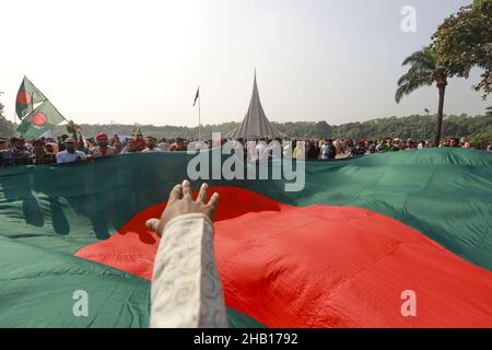 Savar, Bangladesch. 16th Dez 2021. Die Menschen winken Nationalflaggen, während sie sich versammeln, um am nationalen Denkmal der Märtyrer des Unabhängigkeitskrieges 1971 ihren Respekt zu zollen, um den Tag des Sieges 50th zu feiern, der das Ende eines bitteren neunmonatigen Unabhängigkeitskrieges von Pakistan am 16. Dezember 2021 in Savar markiert. Bangladesch feiert den 50th. Jahrestag seines nationalen Sieges und erinnert sich an die tapferen Freiheitskämpfer, die gekämpft und das ultimative Opfer gebracht haben, um das Land von den pakistanischen Truppen zu befreien. Menschen aus allen Gesellschaftsschichten versammelten sich am National Memorial von morgens an auf T Stockfoto