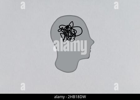 Silhouette eines menschlichen Pappkopfes mit einem Gewirr von Gedanken im Kopf. Mensch auf der Suche nach Ideen Stockfoto