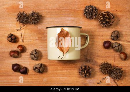 Metallbecher und trockenes Blatt auf einem Holzbrett in der Draufsicht Stockfoto