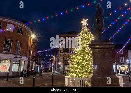 15th. Dezember 2021. Das Stadtzentrum von Romsey in Hampshire, Großbritannien, wurde mit farbenfrohen Weihnachtslichtern dekoriert und beleuchtet. Das Highlight ist der wunderschöne Weihnachtsbaum auf dem Marktplatz, der neben der Statue von Lord Palmerston steht. Stockfoto
