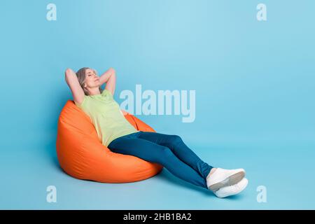 In voller Länge Körpergröße Foto Senior Business Frau entspannen in Sitzsack isoliert pastellblau Hintergrund Stockfoto