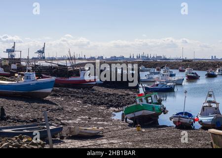 Ein Blick von Paddys Hole, Redcar, England, Großbritannien, zeigt die festgestemmten Boote und den industriellen Hintergrund von Teesport Stockfoto