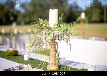 Kerzenständer aus Holz mit grünen Pflanzen in der Mitte des Tisches bei der Hochzeitsfeier im Freien Stockfoto