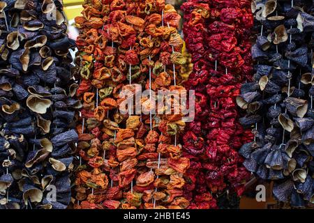 Getrocknetes Gemüse auf traditionelle Weise auf Fäden aufgereiht und auf der Straße aufgehängt. Getrocknete rote, heiße und süße Paprika, Aubergine. Stockfoto