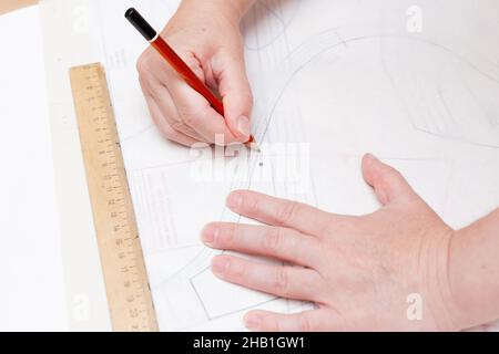 Weibliche Hände machen das Layout des Nähmusters auf Papier Stockfoto