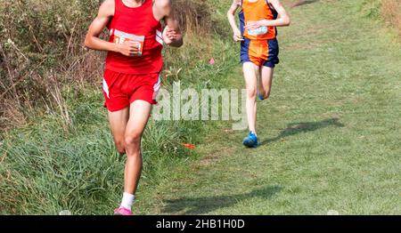 Zwei High-School-Jungs ein Rennen während einer 5K in Bowdoin Park auf einem gut gepflegten Rasenfeld bergab. Stockfoto