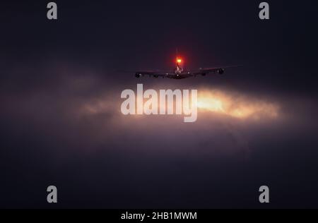 Hamburg, Deutschland. 16th Dez 2021. Ein Airbus A380 der arabischen Fluggesellschaft Emirates fliegt kurz nach dem Start vom Airbus-Werk in Finkenwerder in die Wolken. 16 Jahre nach dem ersten Flug des größten Passagierflugzeugs der Welt lieferte Airbus am Donnerstag die letzten A380 an die arabische Fluggesellschaft Emirates aus. Quelle: Christian Charisius/dpa/Alamy Live News Stockfoto