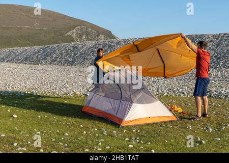 Camping Menschen Outdoor Lifestyle Paar ein Zelt in der Natur felsigen Strand aufzustellen. Stockfoto