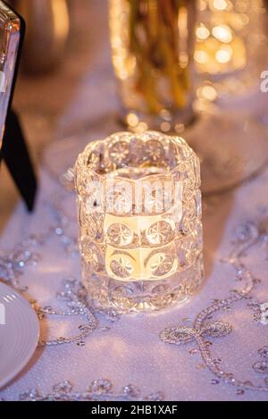 Goldener dekorativer Kerzenhalter aus Glas im Mittelpunkt auf dem Tisch beim Hochzeitsempfang Stockfoto