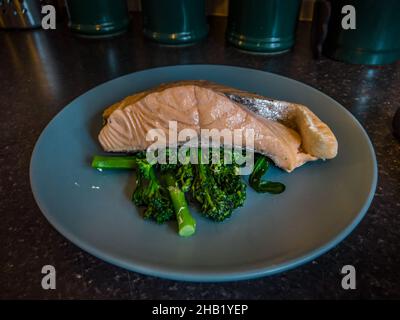 Gedünsteter Lachs und Brokkoli auf einem blauen Teller Stockfoto