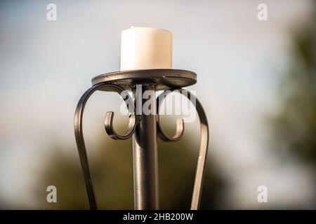 Schwarzer, hoher Kerzenhalter mit weißer Kerze im Freien Stockfoto