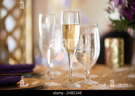 Champagner-gefülltes Glas auf goldenem Tischtuch bei der Hochzeitsfeier Stockfoto