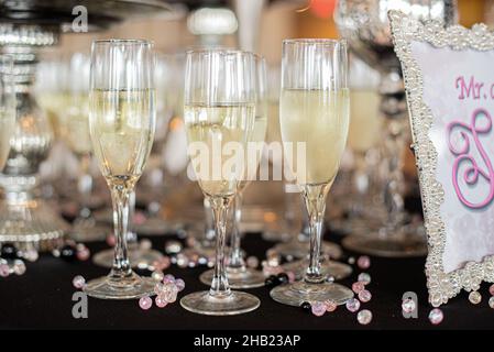 Champagner gefüllte Gläser standen bereit, um bei der Hochzeitsfeier zu dienen, und standen bereit, um sie bei der Hochzeitsfeier mit rosa Perlen zu servieren Stockfoto